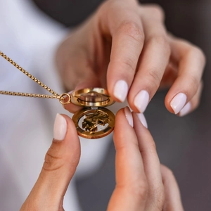 Detailed close-up of a 18k gold-plated locket opening with boy and girl silhouettes