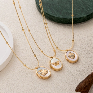 Detail of vintage gold plated necklaces featuring shell pendants with strawberry and butterfly