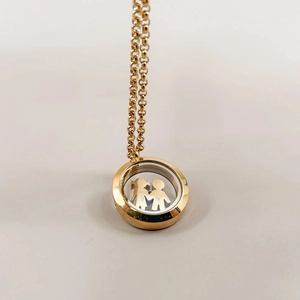 Macro detail of 18k gold locket with hollow figures behind transparent glass