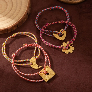 Handmade woven cord bracelets with gold moon, heart, and flower charms on a brown background
