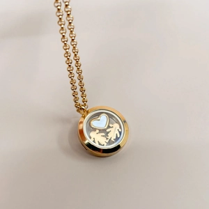 Detailed view of a golden locket pendant with floating heart and girl charms