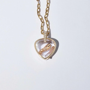 Détail macro d'un médaillon coeur doré contenant un chausson de danse et des diamants fins