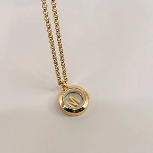 Detail view of 18k gold personalized locket pendant with an internal floating letter M