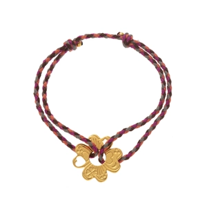 Macro detail of hand-woven rope bracelet featuring a golden flower pendant with heart cutout