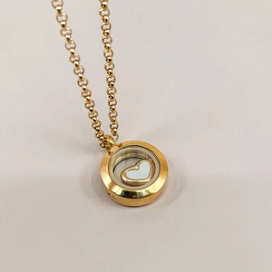 Detailed close-up of a hollow 18k gold pendant with a floating heart design charm
