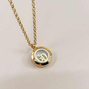 Macro detail of 18k gold vintage pendant with transparent locket and CD initial