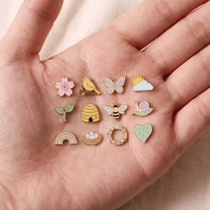 Ensemble de broches émaillées pastel aux motifs de nature sur une paume de main