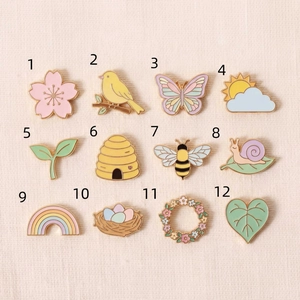 Série de 12 pin's en émail aux tons pastels avec thèmes printaniers et bords dorés