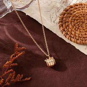 Elegante collana con ciondolo a zucca dorata su carta vintage con decori autunnali