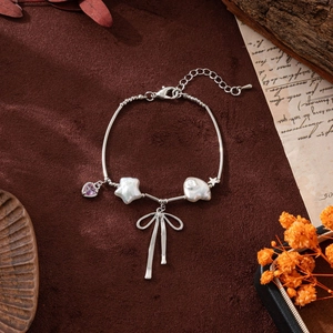 Elegantes Schleifen- und Herz-Perlenarmband mit silbernen Sternanhängern auf Vintage-Grund