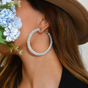 Sparkling silver hoop earrings with triple-row rhinestones worn by a model in a hat