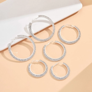 Three pairs of elegant rhinestone hoop earrings in varying sizes on a display tray