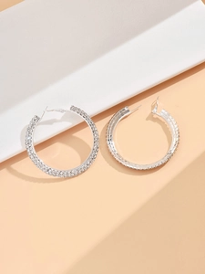 Close-up of silver-tone hoop earrings encrusted with rows of shimmering rhinestones