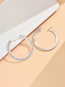 Macro detail of large silver hoop earrings featuring multi-row crystal pavé settings