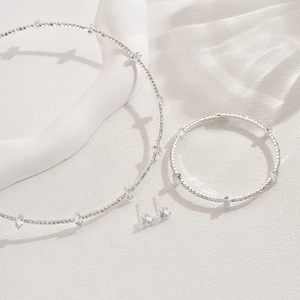 Detailed view of elegant silver jewelry set with marquise cut crystals on a white surface