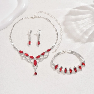 Detail of silver jewelry set with red marquise stones and crystals on white background
