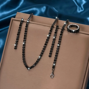 Vue détaillée de l'ensemble de bijoux en strass noirs avec collier, bracelet et bague sur satin