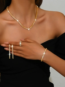 Détail d'un ensemble de bijoux dorés avec collier, bague et boucles d'oreilles portés