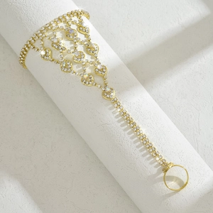 Dettaglio di un bracciale slave dorato con cuori di strass e collegamento all'anello