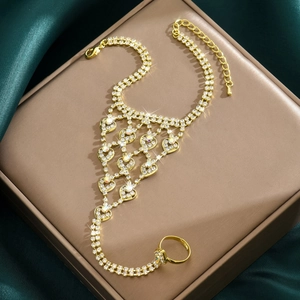 Elegante bracciale anello dorato con cuori di strass su sfondo di seta pregiata