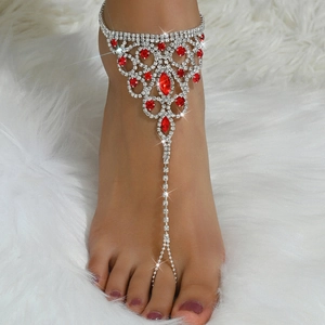 Detail of bohemian silver foot chain with red teardrop gemstones and white rhinestones