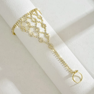 Dettaglio del bracciale anello dorato con strass scintillanti e polsino traforato chic