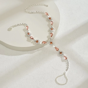 Détail macro de la cheville bohème avec pierres ambrées et strass clairs sur un piédestal