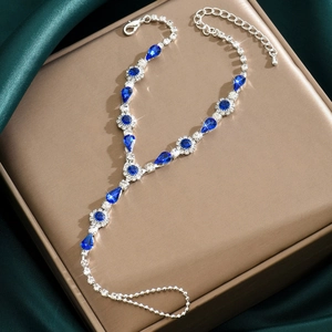 Détail d'un bracelet de doigt argenté avec cristaux bleus en goutte et strass brillants