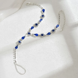 Détail de la chaîne argentée avec des pierres bleues en goutte et strass brillants