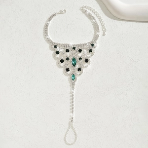 Detail of silver toe ring anklet with sparkling rhinestones and green gems for beach