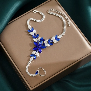 Macro detail of silver hand harness with blue gems and rhinestones on silk fabric