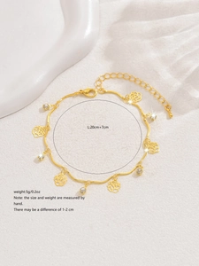 Détail d'un bracelet doré orné de breloques roses évidées et de strass scintillants