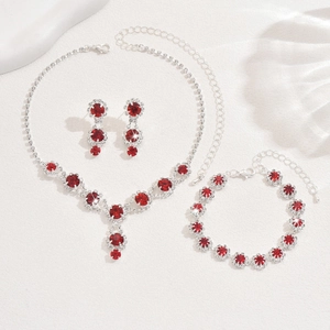 Exquisite bridal jewelry set with red gemstones and sparkling crystals on stone texture