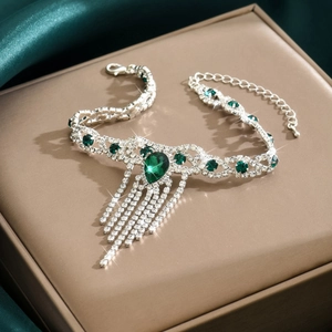 Vista macro detallada de la tobillera de plata con diamantes de imitación verde esmeralda y flecos