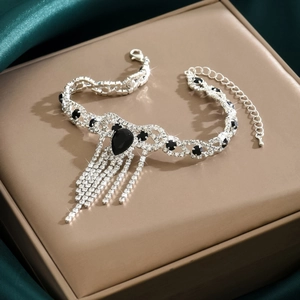 Detalle del tobillera plateada con cristal negro de pera y flecos de pedrería fina