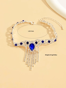 Detalle de tobillera plateada con pedrería azul de gota y colgantes de flecos