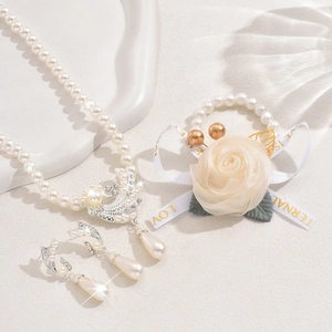 Detail of bridal jewelry set with pearl necklace, swan pendant, and flower wristband