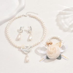 Macro shot of faux pearl bridal jewelry set with flower details and swan pendants