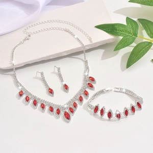 Close-up of bridal jewelry set with red marquise gems and crystals on white marble