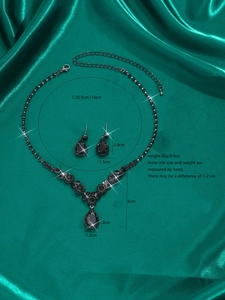Detail view of a black gemstone jewelry set with necklace dimensions on emerald silk
