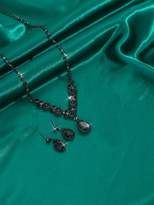 Detailed view of Halloween bridal jewelry set with black teardrop crystals on green satin