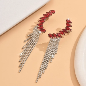 Close-up of elegant long tassel earrings with red pear-cut gems and silver rhinestones