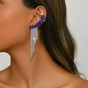 Close-up of bohemian ear cuff with pear-cut blue gems and long silver tassel fringe