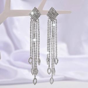 Silver long tassel rhinestone earrings with teardrop hollow pendants on silk background