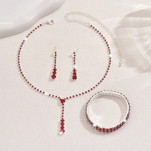 Detail view of silver necklace bracelet and earrings set with vibrant red rhinestones