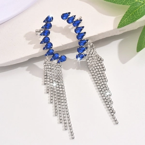 Macro view of long tassel earrings with pear-cut blue stones and silver plating