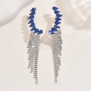 Detail of long tassel earrings featuring deep blue teardrop gems and zircon chains