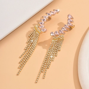 Detailed macro view of gold-tone tassel earrings with pink stones and sparkling rhinestones