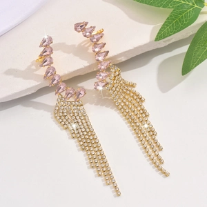Close-up of gold tassel earrings with pink pear gems and sparkling rhinestone chains