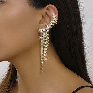 Close-up of luxury gold tassel ear cuff with sparkling teardrop zircons and long diamond chains